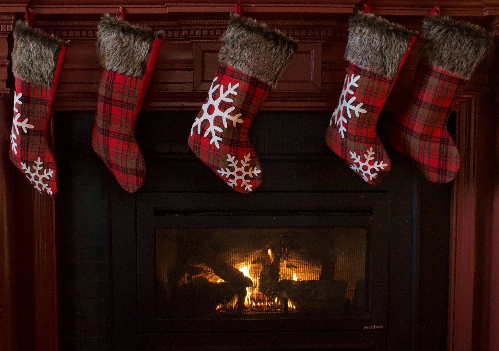 photo of a cosy looking fire hung with Christmas stockings close up
